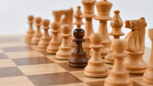 Wooden chess board with carved pieces set for a game in natural sunlight