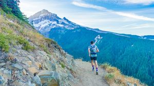 A runner along a mountain ridge under a crisp, bright blue sky in morning sunlight