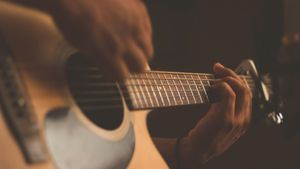 Close-up of hands playing chords on an acoustic guitar