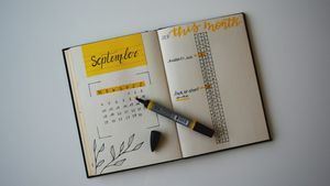 Open monthly calendar planner with a pen on a sunlit wooden desk
