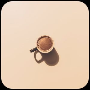 Overhead photo of a cup of coffee on a warm beige background