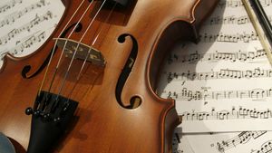 Warm wooden violin and bow resting on printed sheet music