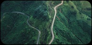 Aerial view of a winding mountain road through lush green hills