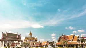 Wat Arun temple towers against a bright blue sky in Bangkok